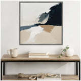 Abstract coastal landscape painting with broad beige, white, and black brushstrokes in a square frame above a wooden console table with books, a mug, and a white vase with greenery.