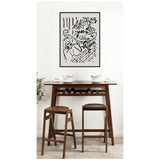 Minimalist dining setup with dark wood table and two stools, featuring a framed black-and-white Henri Matisse print of a seated girl and table on the wall.