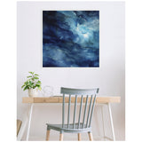Abstract framed canvas with swirling shades of blue and white evoking watery textures, displayed above a wooden desk with a plant and decorative wire sculpture.
