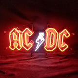 Red neon sign displaying 'AC' and 'DC' with a white lightning bolt between the letters on a black background at night.
