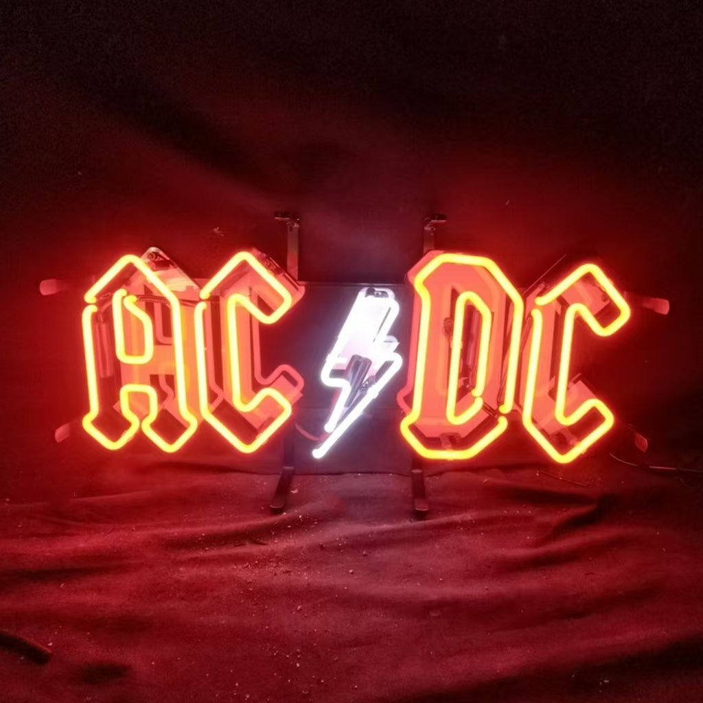Red neon sign displaying 'AC' and 'DC' with a white lightning bolt between the letters on a black background at night.
