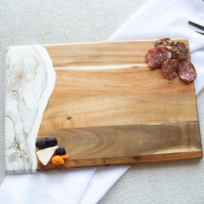 acacia resin serving bread board with sliced meats and fruits on a marble and wood surface