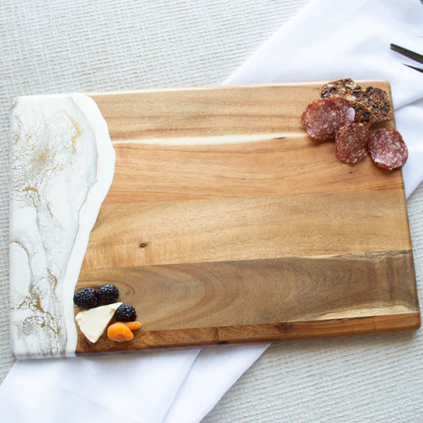 acacia resin serving bread board with sliced meats and fruits on a marble and wood surface