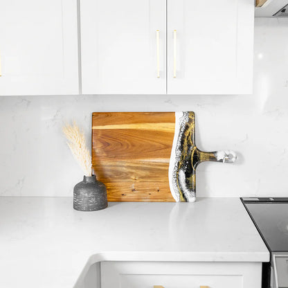 Wooden charcuterie serving tray with a decorative handle on a kitchen counter.
