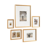 Five gold-framed wall picture frames in various sizes arranged with white mats, displaying photos of couples and a woman outdoors in soft, natural light.