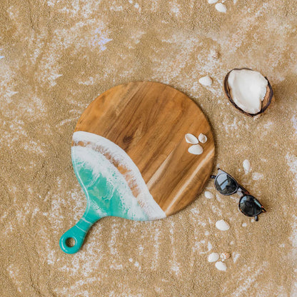 Wooden paddle with green handle on sandy surface