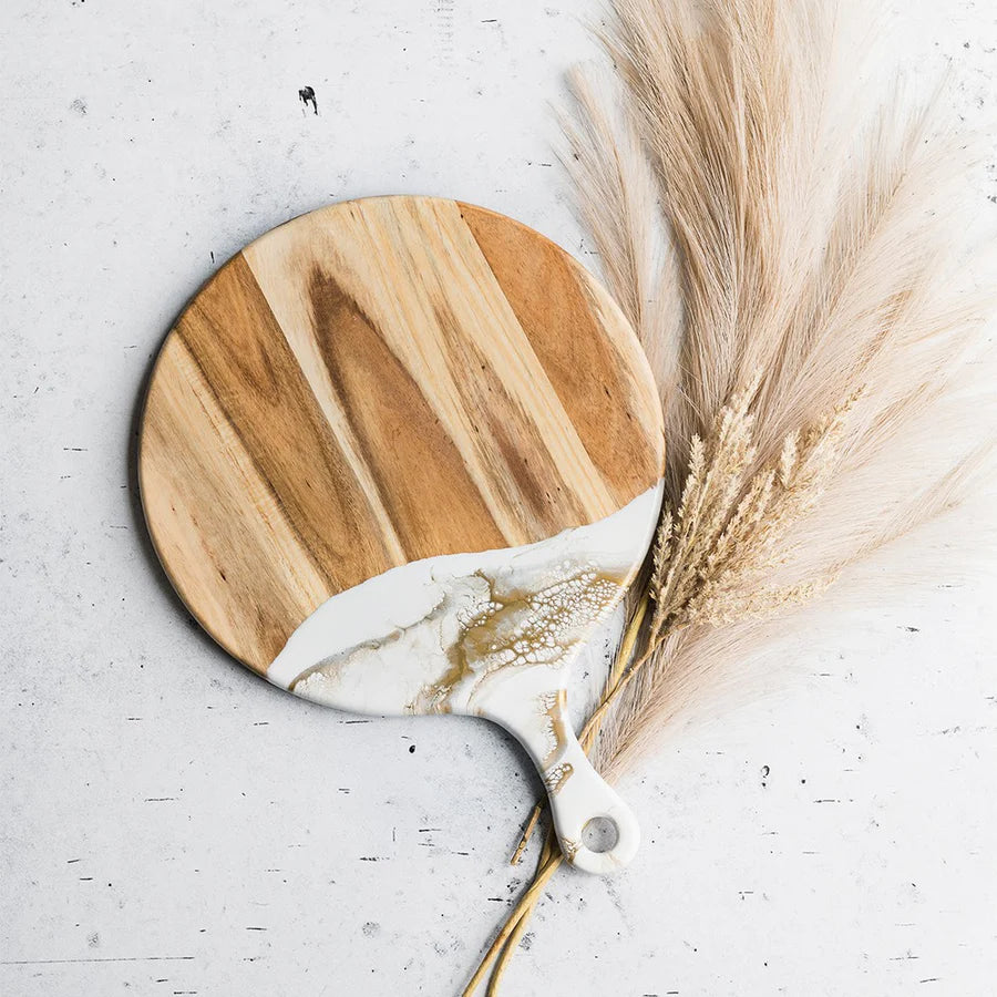 Round wooden Cheese Paddle Acacia Serving Charcuterie Board with marble-like finish on a light gray surface with dried pampas grass.
