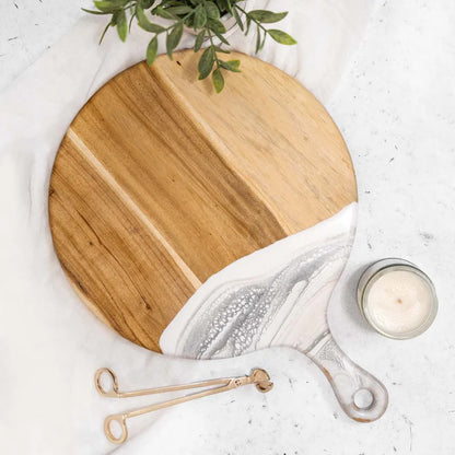 Round wooden Cheese Paddle Acacia Serving Charcuterie Board on a marble surface with a candle and plant