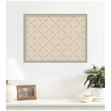Wall-mounted green lattice print with diamond-shaped pattern on beige background, framed in muted green, above a white shelf with lamp, photo frame, and potted plant.