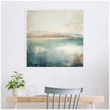 Framed abstract landscape canvas above a light wood desk, featuring soft blue and beige tones that evoke a calm lake scene, with a green potted plant and chair nearby.