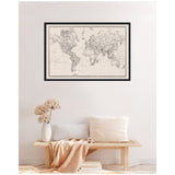 Framed vintage black and white linen world map with detailed continents and oceans, hanging above a minimalist wooden bench with neutral pillows and dried flowers.