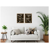 Two framed abstract canvas art pieces with neutral tones and organic shapes hang above a white sofa adorned with patterned and solid pillows, flanked by green plants.
