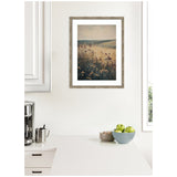 Framed print of a serene landscape with wildflowers in the foreground and rolling hills under a muted sky, hanging on a bright white kitchen wall.