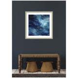 Abstract framed artwork featuring swirling shades of rich blue and white, hung on a dark wall above a carved wooden bench with woven seats and two fabric baskets underneath.