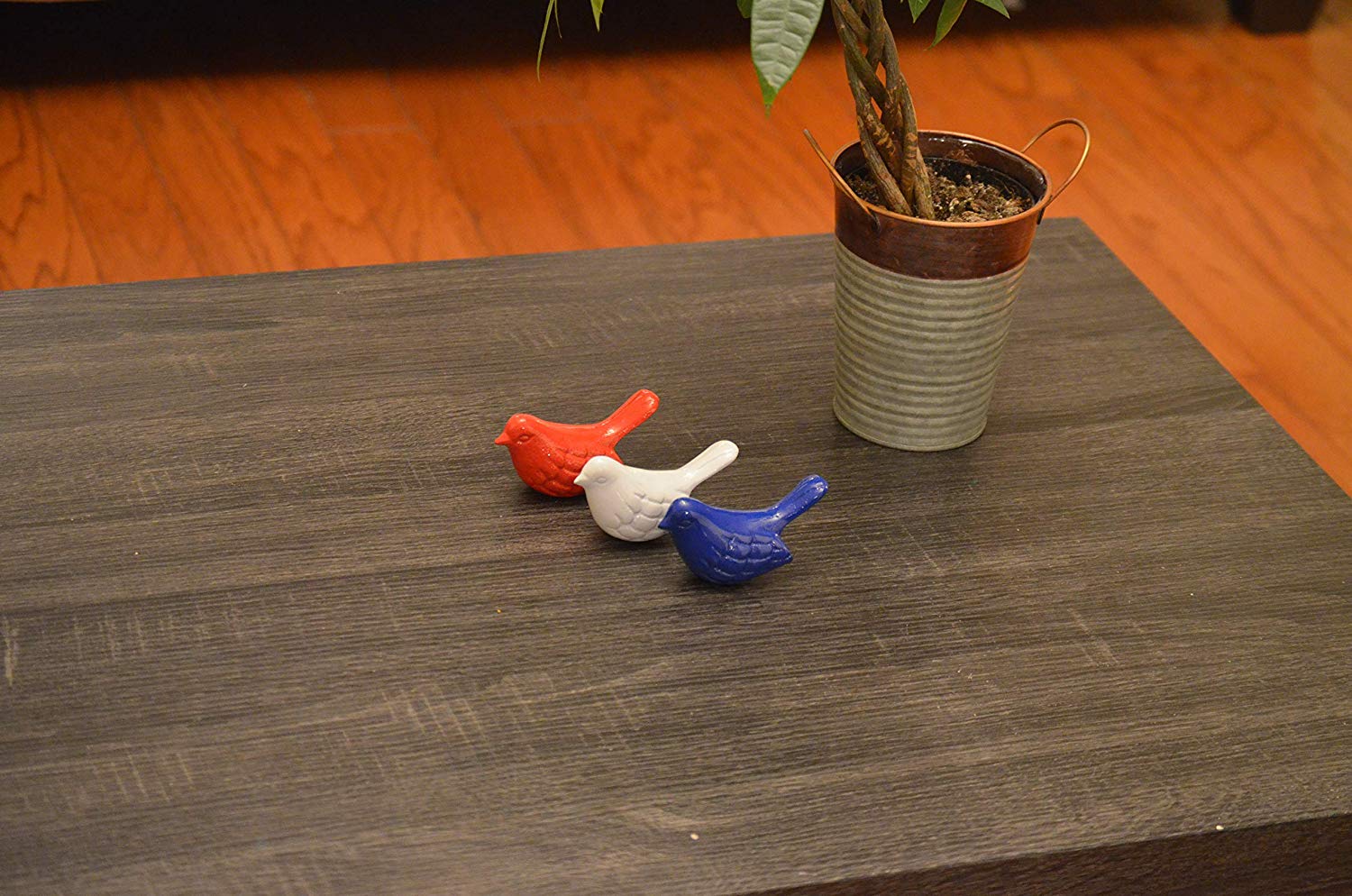 Set of three Vibhsa aluminum bird figurines in blue, red, and white colors arranged on a wooden surface