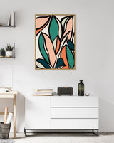 Abstract botanical artwork with large stylized leaves in teal, peach, and coral outlined in black on a white background, framed and hung above a white sideboard.