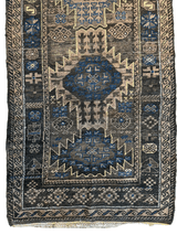Antique 1880s Baluch wool rug with muted blue, beige, and brown geometric medallions and a patterned border on a dark field.