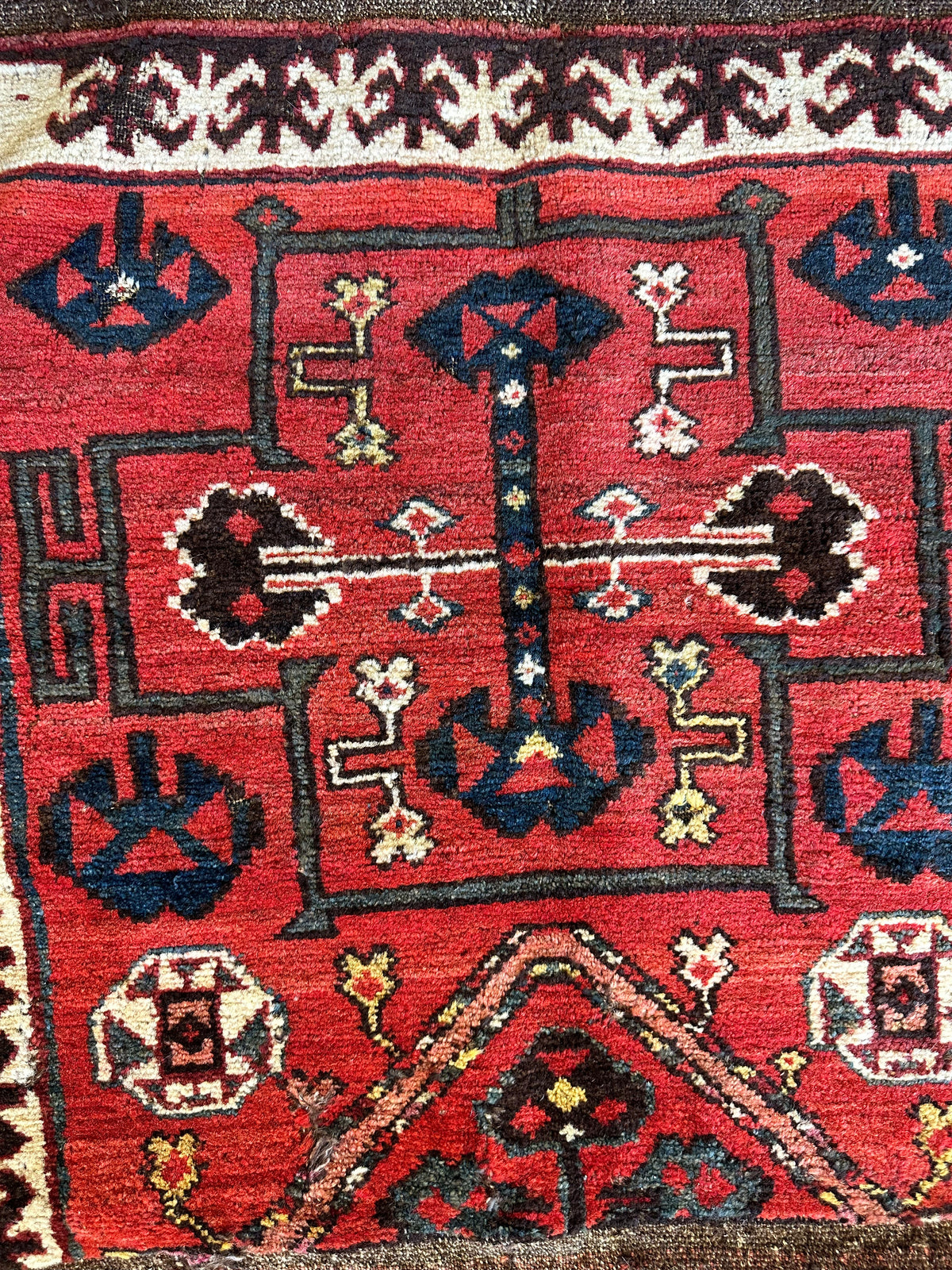 Antique tribal bagface with deep red background featuring intricate black, white, and blue geometric patterns framed by a dark border and a cream decorative edge.
