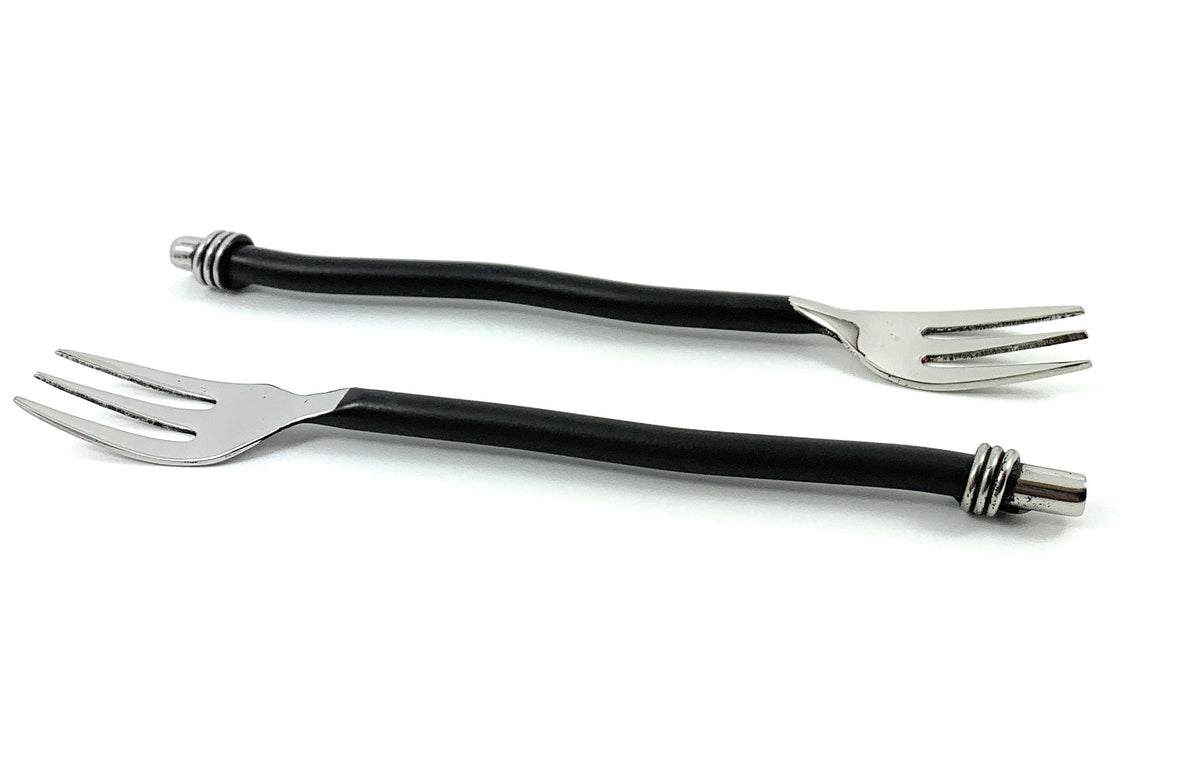 Two metal cocktail forks with curved black twisted handles and three short tines, each handle ending with a decorative silver ring and cap.