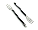 Set of six black twisted handle cocktail forks arranged on a dark surface
