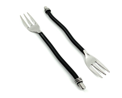 Set of six black twisted handle cocktail forks arranged on a dark surface