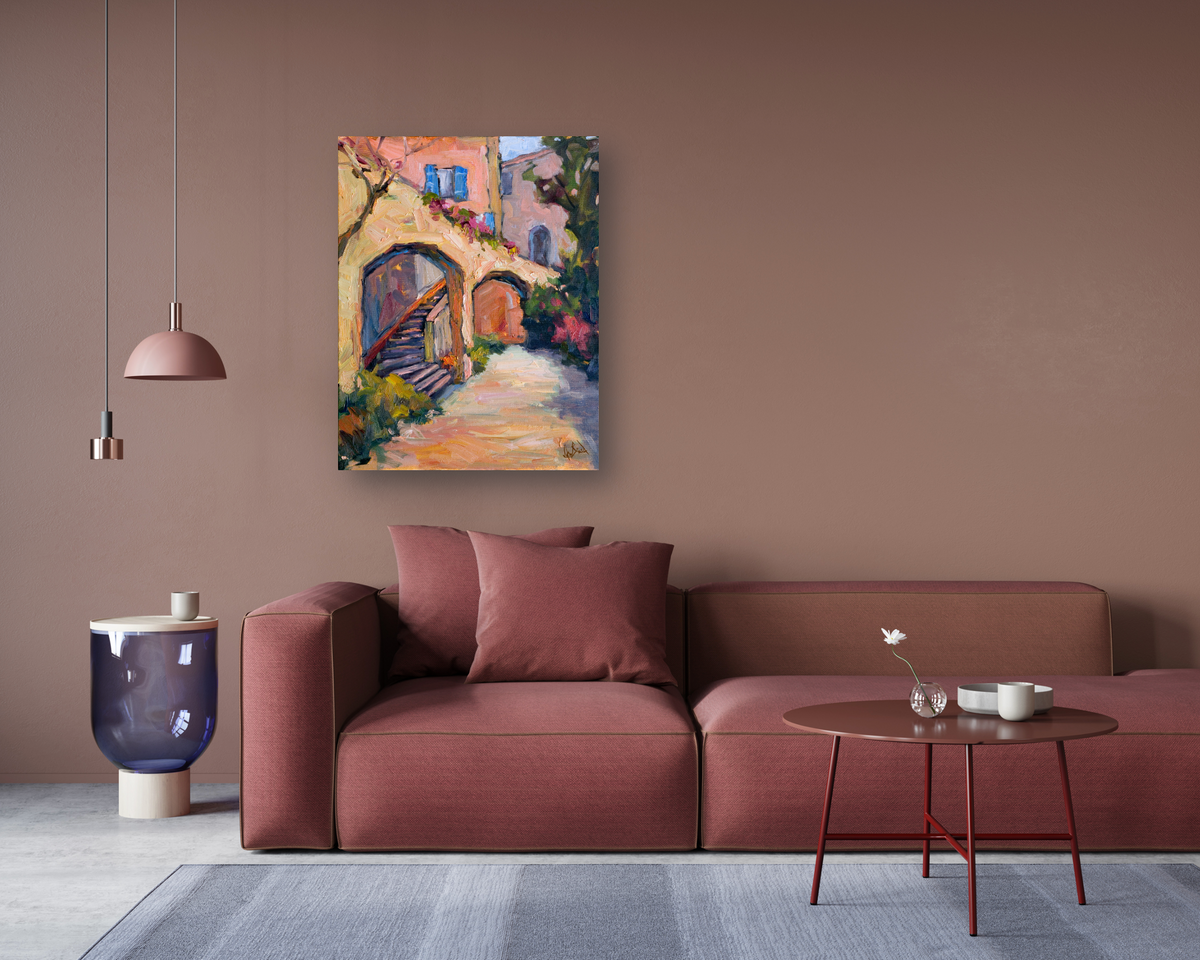 Impressionist painting of sunlit arches and stairs in warm tones of orange, pink, and purple, hanging above a muted rose sectional sofa in a modern living room.