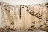 Close-up of a rectangular pillow featuring a vintage rug fragment pattern in muted beige, brown, and faded coral tones with vertical stitched texture.