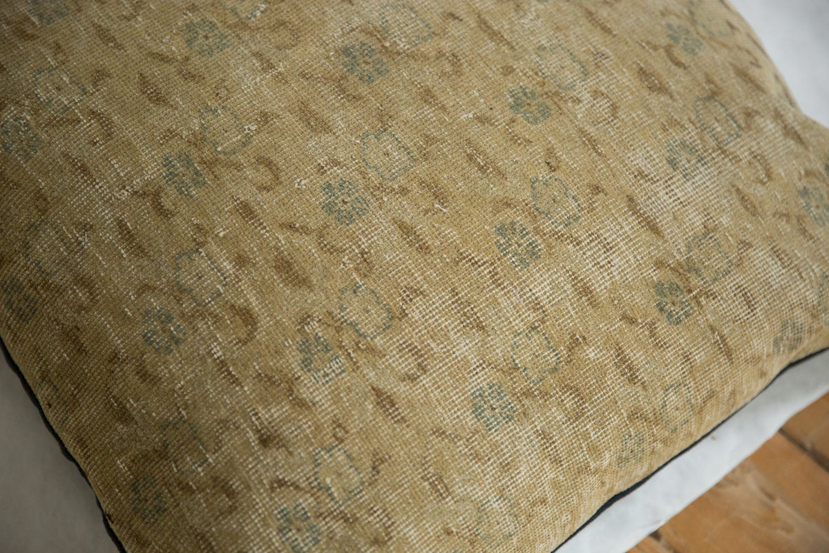 Close-up of a beige vintage Turkish Sivas rug fragment pillow with faded floral and geometric patterns in muted blue and brown tones on textured fabric