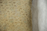 Close-up of a vintage Turkish Sivas rug fragment pillow with muted beige and light blue patterns on a soft woven fabric.