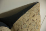 Corner of a pillow featuring a beige fabric with faded turquoise and brown floral patterns next to a solid dark navy blue fabric section.