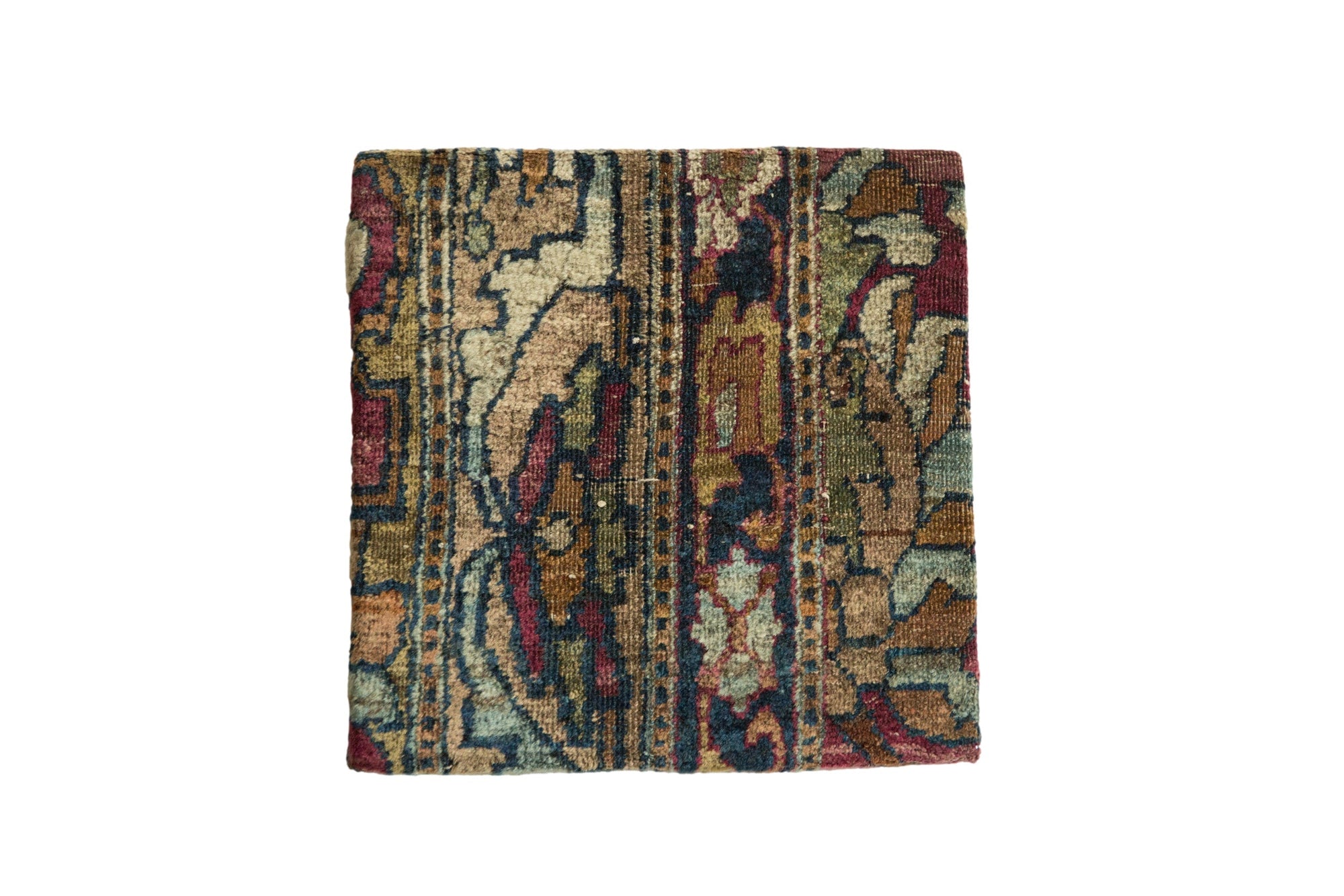 Decorative cork board featuring an antique Kerman rug fragment with rich floral patterns in warm reds and blues, framed and set as wall art