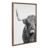 Black and white portrait of a Highland cow facing forward with long hair partially covering its eyes and large curved horn visible, framed in wood.