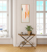 Abstract framed canvas featuring layered vertical brushstrokes in peach, orange, yellow, and navy hangs centered on a white paneled wall above gold and glass bar cart with potted plant.