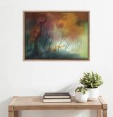 Framed canvas painting depicting faint stag silhouettes among bare trees with a misty forest background in warm orange and cool green hues.