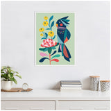 Framed canvas art showing a stylized dark blue cockatoo with geometric patterns perched on a colorful floral branch against a pale green background.
