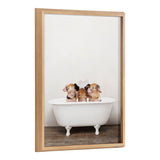 Three small piglets sitting inside a white vintage clawfoot bathtub on a wooden floor with a plain white background, framed in light natural wood.