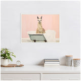 Framed illustration of a llama sitting inside a vintage bathtub with a folded white towel, set against a pastel pink wall above a minimalist white shelf with plants and books.