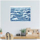 Framed linocut artwork depicting abstract blue and white ocean waves with flowing, textured lines, hung above a wooden desk featuring minimalist decor.
