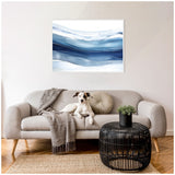 Gray sofa with a hound dog lying on it, textured gray throw and round cushion, black metal lattice coffee table with potted plant, and abstract blue-hued framed artwork above.