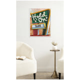 Framed canvas print of a retro green marquee sign with white letters saying "Hold On" above a lightbox reading "To Your Shorts" mounted on a white wall above a bronze side table with a white vase.