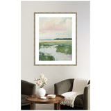 Framed abstract landscape painting with soft pink and blue sky over green marshland, hanging above dark armchairs and a wooden coffee table with white vase and decor.