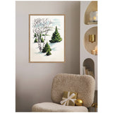 Framed canvas of snowy scene with two green fir trees and one leafless birch tree, displayed on a beige wall above a textured beige chair with a gold gift box and ornament.
