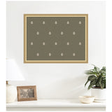 Olive green wall art featuring a repeated white botanical leaf block print pattern in a gold-toned frame above a white surface with lamp, photo frame, and potted plant.