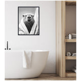 Black and white framed canvas of a capybara wrapped in a towel, hung above a white freestanding bathtub with a towel draped over its edge in a modern bathroom.