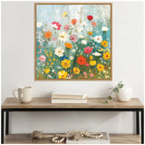 Square framed canvas painting of a boho wildflower garden featuring colorful red, pink, orange, yellow, and white flowers with green stems and a teal background above a wood console table.