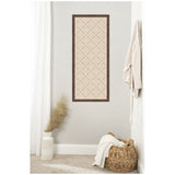 Rectangular cork pinboard with a dark wood frame and a diamond lattice pattern of black pins on beige cork, mounted on a light gray wall above a wicker basket and white vase.