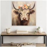 Square framed canvas painting of a highland cow with long beige fur and curved dark horns, adorned with a colorful floral crown, hanging above a wooden shelf setup.