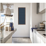 Tall rectangular framed navy blue fabric pinboard with white grid lines, mounted on a white wall in a bright kitchen space with gray countertops and light cabinetry.