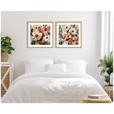 Two framed abstract floral prints featuring cream, peach, orange, and navy blooms with green leaves, hung above a white bed in a minimal bedroom setting.