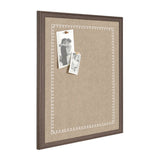 Rectangular beige fabric pinboard with white scalloped edge pattern, framed in medium brown wood, holding two black-and-white photos pinned near top left corner.